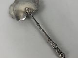 a silver spoon with a flower on it on a white surface