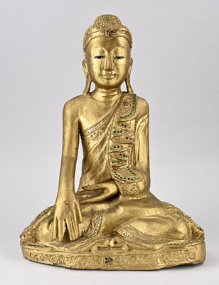 une statue en or représentant un Bouddha assis sur un rocher