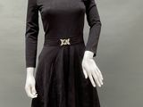 a mannequin wearing a black dress and hat with a gold broochet