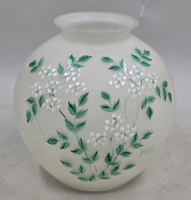un vase blanc orné de fleurs vertes et blanches peintes dessus