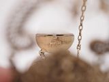 a small gold object hanging from a chain on a table