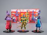trois figurines représentant des personnages de Dragon Ball exposées devant une boîte remplie de livres