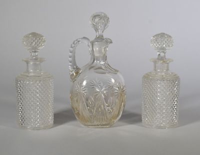 trois bouteilles en verre et une carafe posées sur une table