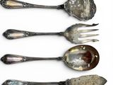 four spoons and a fork are lined up on a white surface