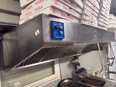 une photo d'une cuisine professionnelle où des pizzas sont empilées les unes sur les autres