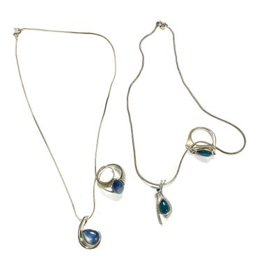 two silver necklaces with blue stones on a white background