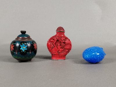 three small vases and a blue ball on a gray surface