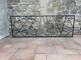 a black iron fence on a brick floor near a stone wall