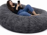 La femme est assise sur le pouf et utilise son téléphone portable.