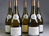 quatre bouteilles de vin blanc sont alignées sur une table