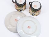 two cups and a saucer sitting on top of a white table