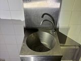 a stainless steel sink in the corner of a bathroom