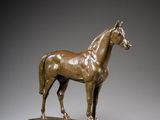 bronze statue of a horse standing on a wooden base