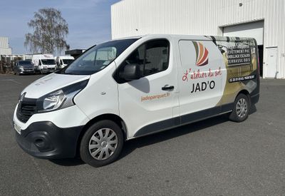 une camionnette blanche garée sur un parking près d'un immeuble