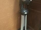 un télescope noir et argenté posé sur un trépied, à côté d'une porte marron