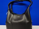 un sac à main en cuir noir posé sur une table, sur fond bleu