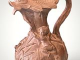 a brown vase with a bird on it on a white background