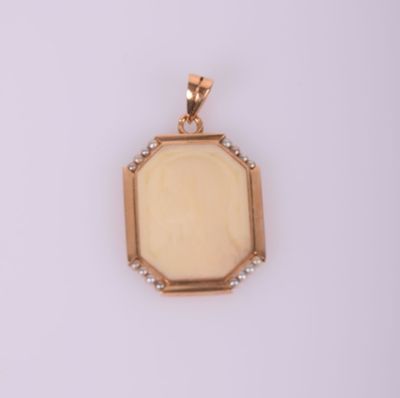 un pendentif en or orné d'une pierre blanche au centre
