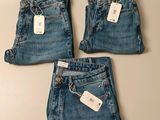 three pairs of jeans with tags on them sitting on a table