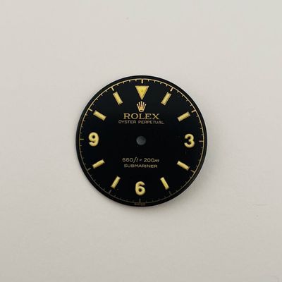 a close up of a black and gold clock on a white wall