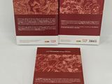 two books on a white surface with a red cover