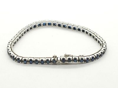 un gros plan d'un bracelet orné de pierres bleues sur un fond blanc