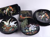 quatre boîtes noires ornées d'oiseaux et de fleurs, posées sur une table
