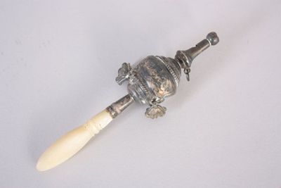 une cuillère en argent avec un manche en bois posée sur une surface blanche