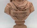 statue of a woman wearing a shawl and holding a basket on a pedestal