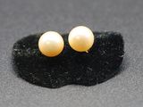 pair of yellow pearl stud earrings on a black surface