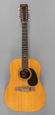 un gros plan d'une guitare acoustique sur fond gris