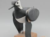 une image représentant un oiseau en noir et blanc posé sur un socle en bois