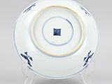 blue and white plate with a gold rim on a stand