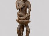 une petite statue en bois représentant un homme tenant un bol