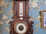 une horloge accrochée au mur dans une pièce, avec un mur tapissé derrière elle