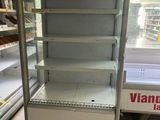 une vitrine vide dans un magasin dont les rayons regorgent de produits alimentaires