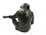 black sculpture of a man sitting on his knees with his legs crossed