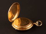 a gold pocket watch on a black surface