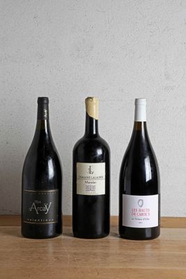 three bottles of wine are lined up on a wooden table