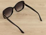 sunglasses on a wooden table with a black frame and brown lens