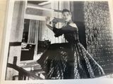 black and white photograph of a woman in a dress holding a large piece of wood