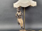 a lamp that has a woman holding a lamp shade on it