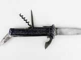 un petit couteau au manche noir posé sur une surface blanche