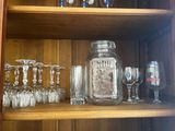 bottles and glasses on a shelf in a wooden cabinet