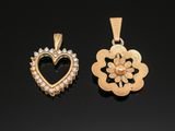 two gold and diamond heart pendants on a black surface