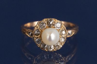 un gros plan d'une bague en perle et diamant posée sur une surface bleue