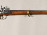 un vieux fusil accroché au mur, à côté d'un mur blanc