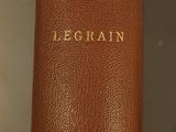 an old book with gold lettering sitting on top of a glass shelf