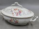 a white bowl with flowers on it on a table