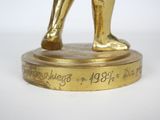 a gold statue of a man holding a tennis racquet